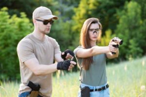 An instructor teaches a woman how to shoot a pistol