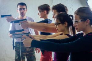 An instructor looks on as his students practice shooting guns